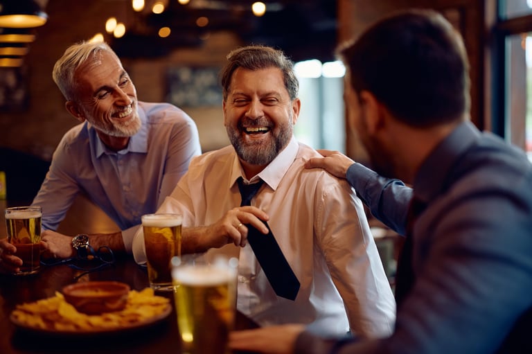 Cheerful businessman talking to his male colleagues while drinking beer in a pub.